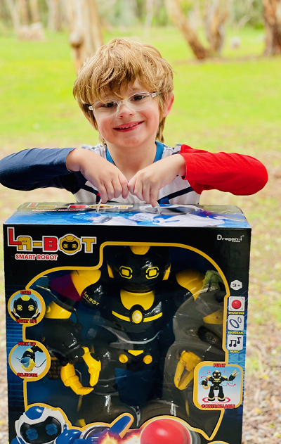 A young smiling boy holding a new robot toy that's been given to him